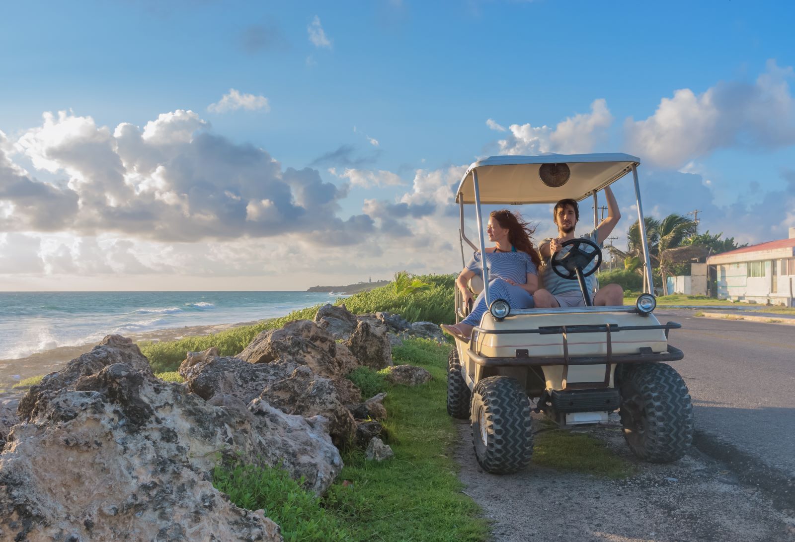couple riding in golf cart exploring the beach